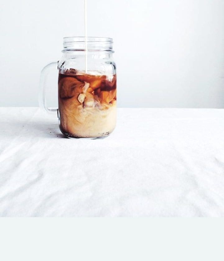 Cold brew and milk swirling in a mason jar