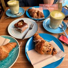 Croissants and cake on blue plates with matcha lattes
